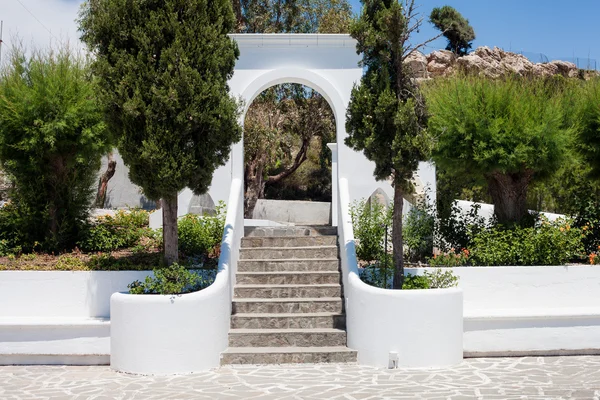 Escadaria com um arco branco, rodeado por arbustos — Fotografia de Stock