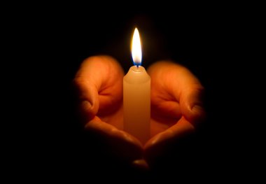 Yanan bir mum tutan eller