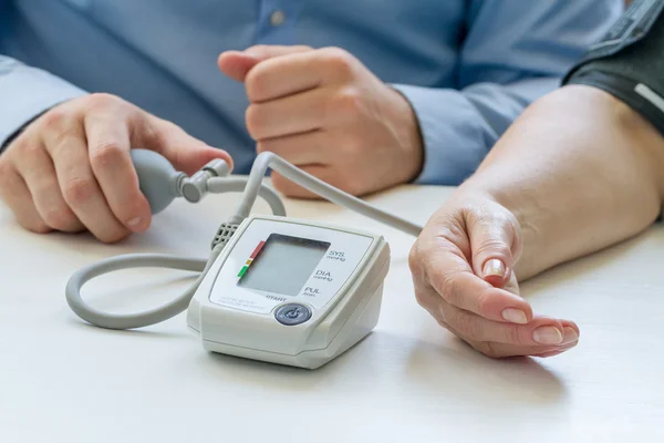 Doctor measuring blood pressure — Stock Photo, Image