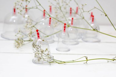 Beyaz ahşap arka planda ve beyaz çiçeklerde hijama için kavanozlar. Kan alma. Sunnah tedavisi. İslam.