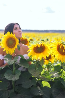 Sahada beyaz bluzlu, ayçiçekli güzel esmer kadın. Sarı ayçiçekleri. Planı kapat.
