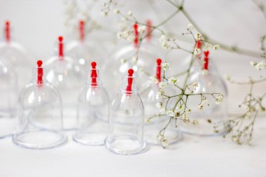 Beyaz ahşap arka planda ve beyaz çiçeklerde hijama için kavanozlar. Kan alma. Sunnah tedavisi. İslam.