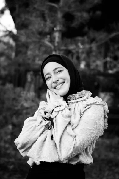 Muslim woman in hijab on the background of trees. Pink blouse and black skirt. Beautiful young woman. Close-up. Black and white photography
