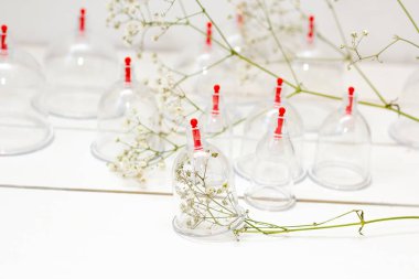 Beyaz ahşap arka planda ve beyaz çiçeklerde hijama için kavanozlar. Kan alma. Sunnah tedavisi. İslam.