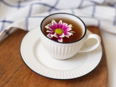 Bir fincan çay ve bir çiçek. Tahta tepside bir bardak ve havluyla. Bahar konsepti Şefkat ve kadınlık
