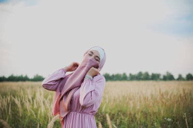 Buğdaylı pembe tesettürlü Müslüman kadın.