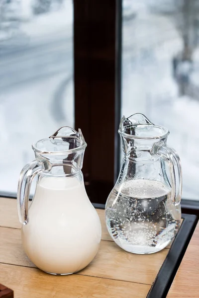 Two jugs. One with water and one with milk. Pitchers on the table