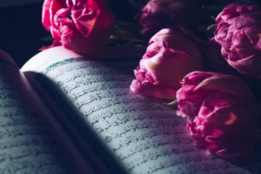 Kazan, Rusya - 03 Mart 2021. Siyah arka planda çiçekli kutsal Kuran. Laleler. Ramazan. Kuran okuyarak. Ramazan kavramı.