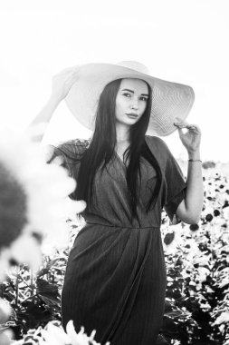 Ayçiçeği tarlasında mavi elbiseli esmer kadın. Güneşli bir gün. Siyah beyaz fotoğraf.