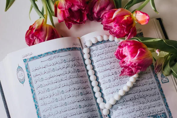 Kazan, Rusya - 03 Mart 2021. Beyaz arka planda çiçekli kutsal Kur 'an ve tespih. Laleler. Ramazan. Kuran 'ın Hatm' ı. Kuran okuyarak. Ramazan kavramı.