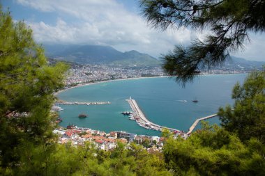 Türkiye 'de deniz, ağaçların arasından Alanya. Arka planda deniz feneri var. Yukarıdan görüntüle