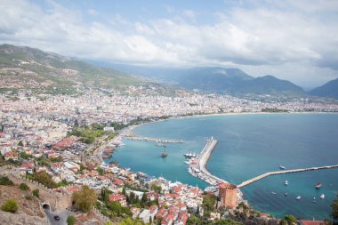 Türkiye 'de deniz, ağaçların arasından Alanya. Arka planda deniz feneri var. Yukarıdan görüntüle