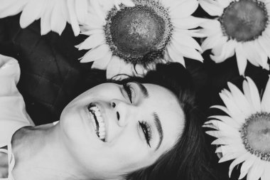 Sahada elinde ayçiçekleri olan sarı elbiseli esmer bir kadın. Turuncu elbise. Yakın plan. Butey. Yüzünü yaklaştır. Siyah beyaz fotoğraf.