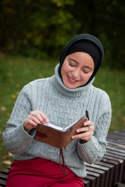 Een Jonge Moslimvrouw Een Grijze Trui Zit Met Een Notitieboekje — Stockfoto