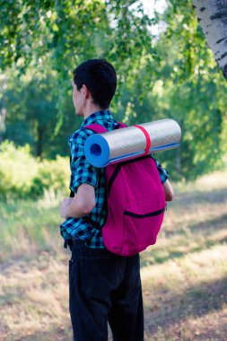 Ormanda sırt çantası ve yürüyüş paspası olan bir adam. Ormanda yürüyüş. Seyahat. Pembe sırt çantası..