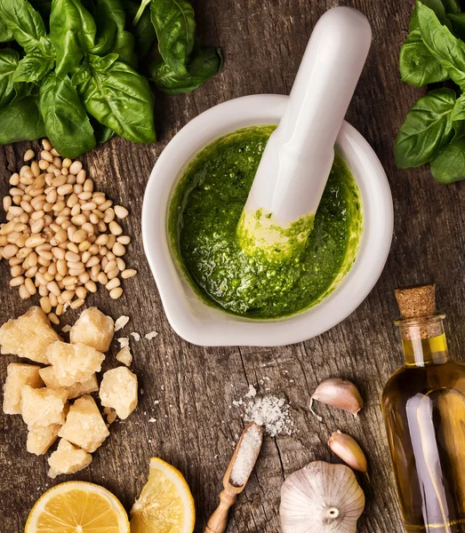 Sauce pesto and its ingredients on rough wood — Stock Photo, Image