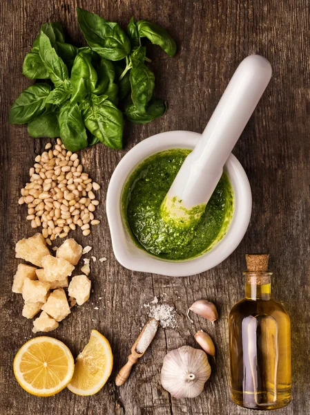 Sauce pesto and its ingredients on rough wood — Stock Photo, Image