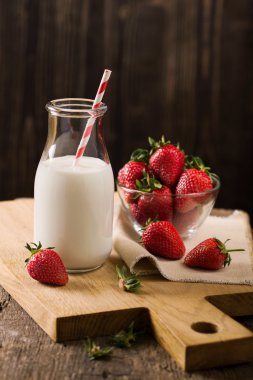 Süt ve çilek kaba ahşap üzerinde karanlık natürmort