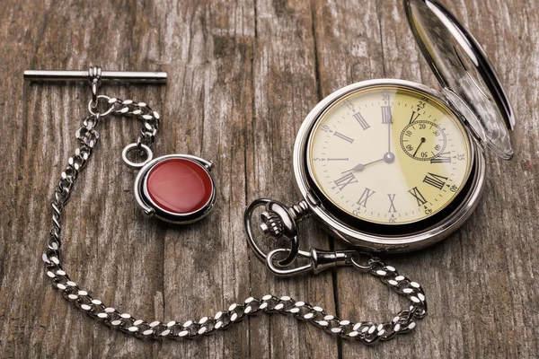 Old fashioned pocket watch with chain on rough wood — Stock Photo, Image