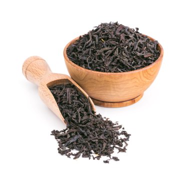 Siyah çay kuru yapraklar üzerinde beyaz izole bir ahşap kase