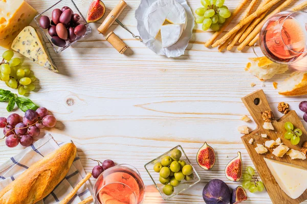 Diversi tipi di formaggi, vino e snack sul bianco in legno — Foto Stock