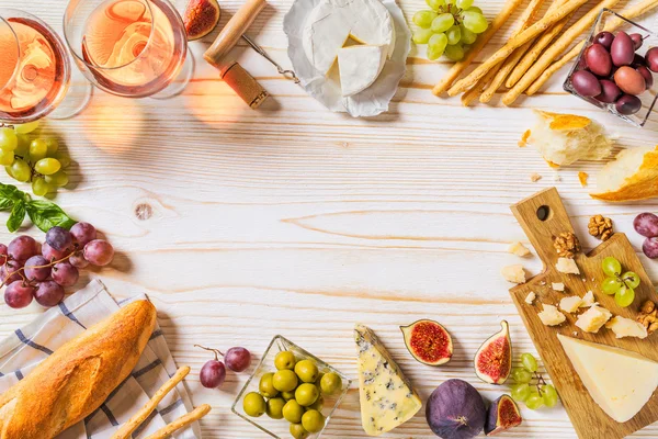 Diversi tipi di formaggi, vino, baguette e frutta su bianco Immagine Stock