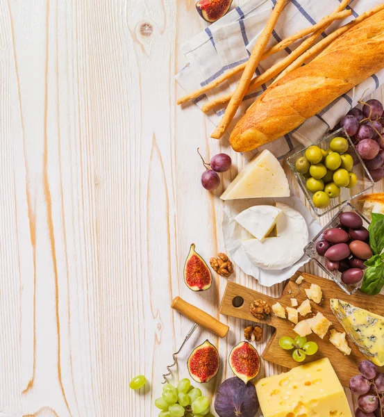 Diversi tipi di formaggi, vino e snack sul legno bianco — Foto Stock