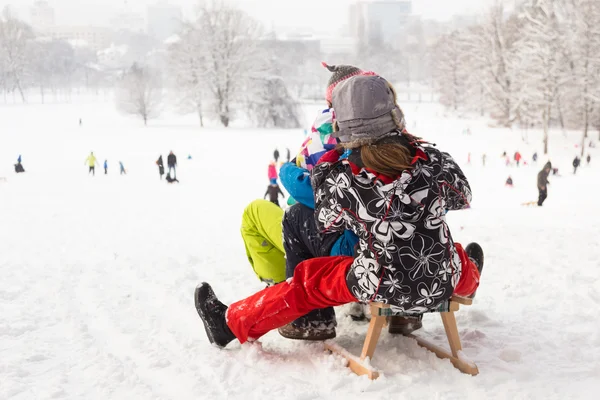 Winter plezier, sneeuw, kinderen rodelen op de wintertijd. — Stockfoto
