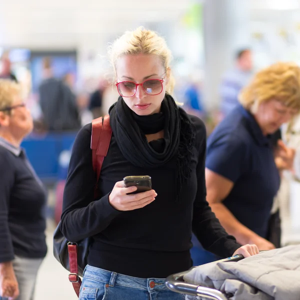 Viajero femenino usando el teléfono celular mientras espera . —  Fotos de Stock