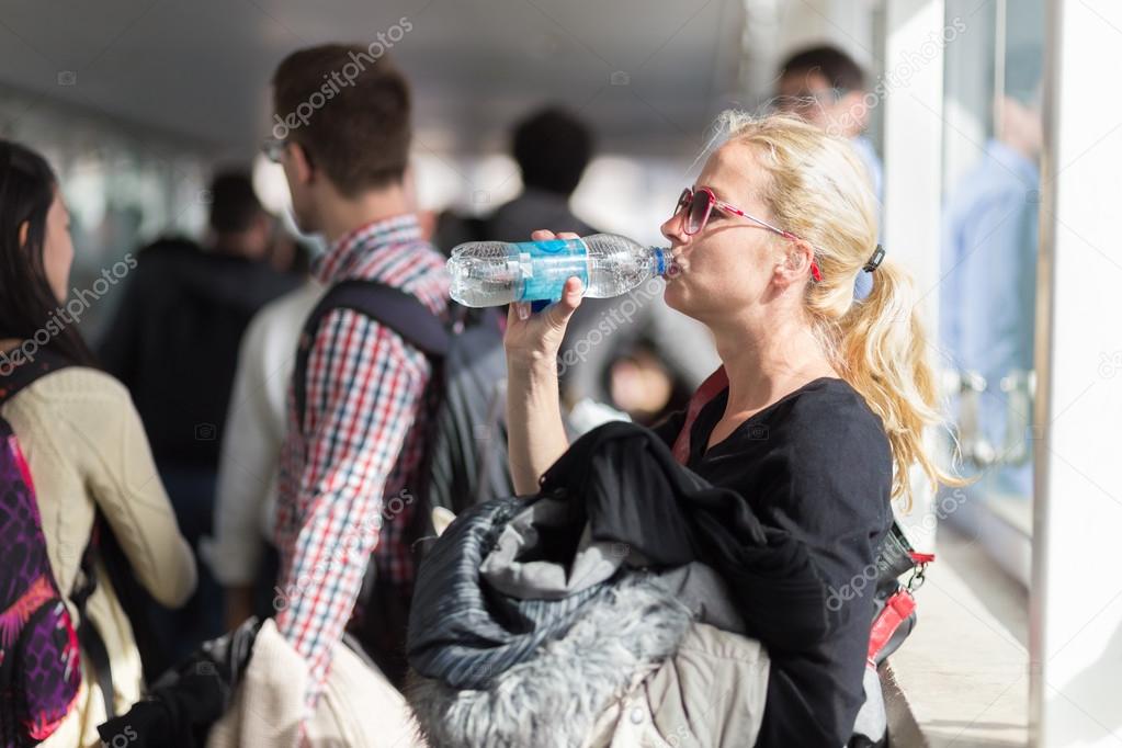 Woman drinking water while queuing to board plane.