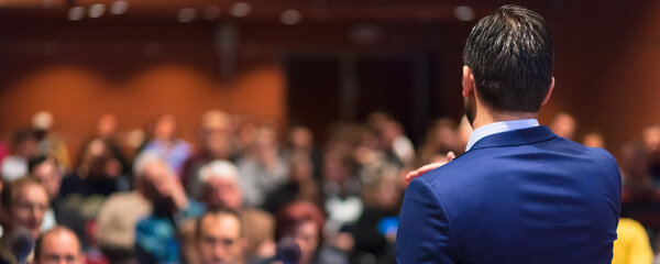 Public speaker giving talk at Business Event.