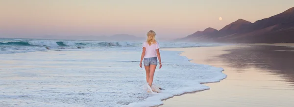 Lady walking on sandy beach in sunset. — Stock Photo, Image