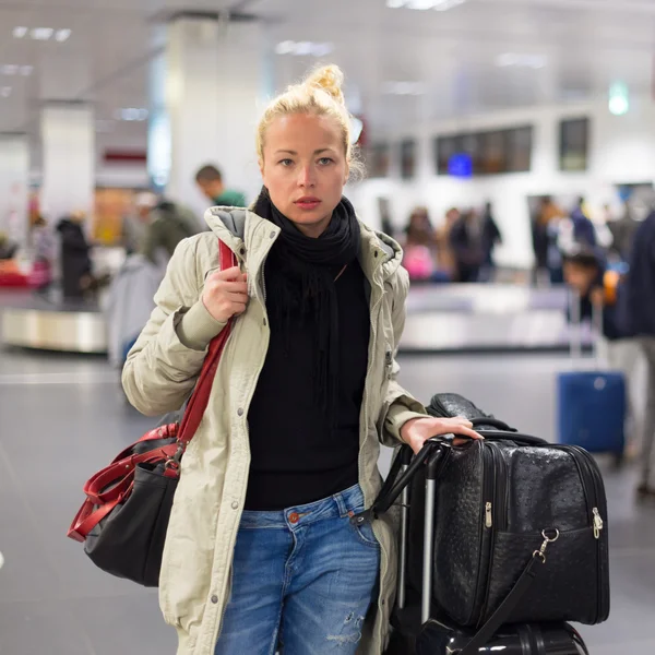 Жінка-мандрівник перевозить свій багаж у терміналі аеропорту . — стокове фото