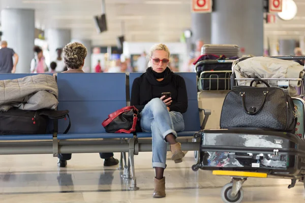 Viajero femenino usando teléfono celular mientras espera en el aeropuerto . —  Fotos de Stock