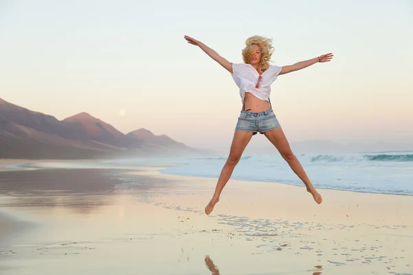 Молода красива жінка стрибає на пляжі . — стокове фото