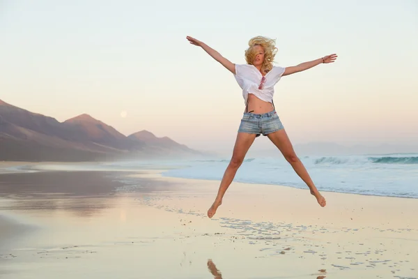 Young beautiful woman jumping in the beach. Stock Photo