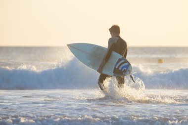 Sörfçü surfboard ile plajda silüeti.