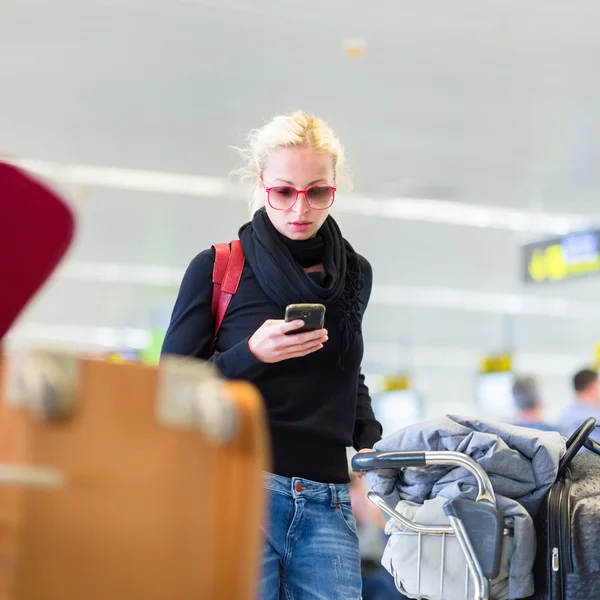 Viajero femenino usando teléfono celular mientras espera en el aeropuerto . — Foto de Stock