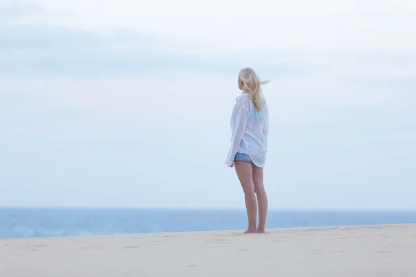 Mulher na praia de areia em camisa branca ao entardecer . — Fotografia de Stock