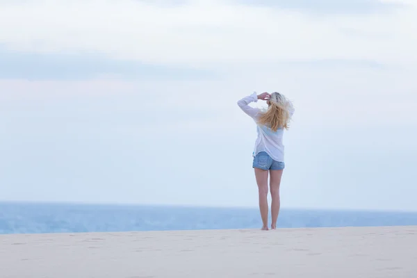दोपहर में सफेद शर्ट में रेत समुद्र तट पर महिला . — स्टॉक फ़ोटो, इमेज