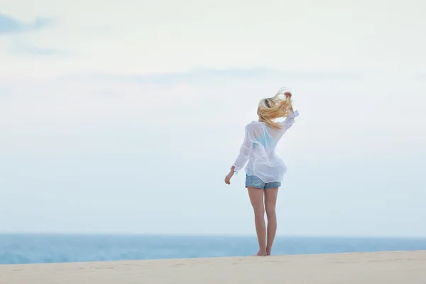 Frau am Sandstrand in weißem Hemd am Morgen. — Stockfoto