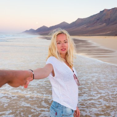 Romantik Çift, elele, kumsalda eğleniyor.