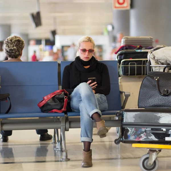 Viajero femenino usando teléfono celular mientras espera en el aeropuerto . —  Fotos de Stock