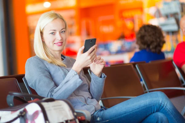 Viajero femenino usando el teléfono celular mientras espera . —  Fotos de Stock
