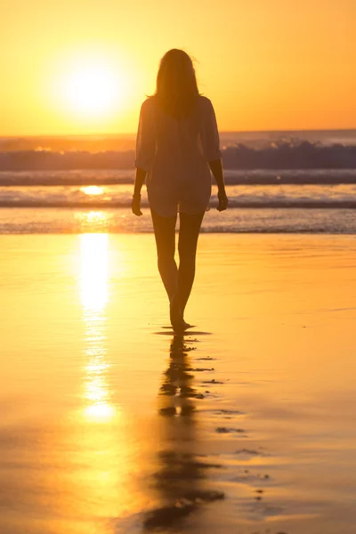 Lady lopen op het zandstrand in de zonsondergang. — Stockfoto