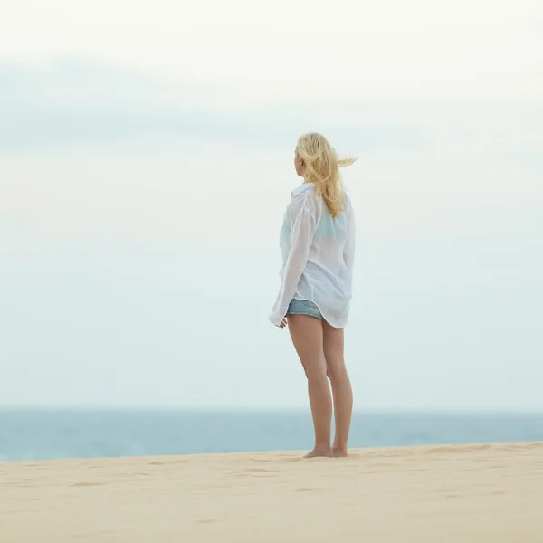 Mujer en playa de arena en camisa blanca al atardecer . —  Fotos de Stock