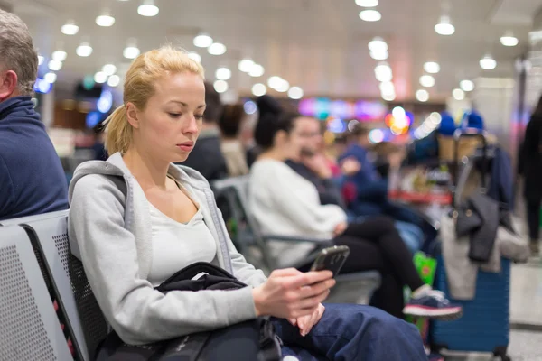 Viajero femenino usando el teléfono celular mientras espera . —  Fotos de Stock