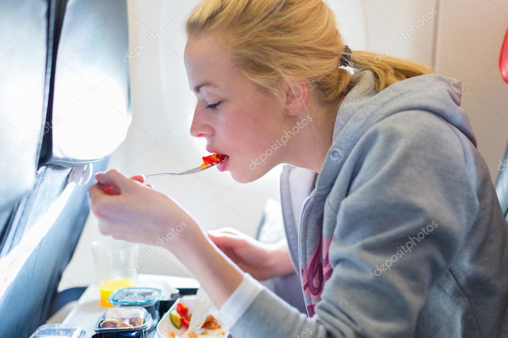 Woman eating meal on airplane.