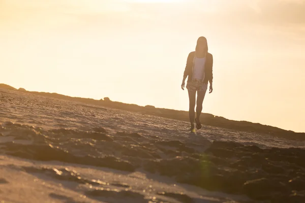 Žena na skalnaté pláži v západu slunce. — Stock fotografie