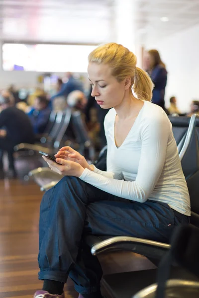 Женщина-путешественница с помощью мобильного телефона во время ожидания . — стоковое фото